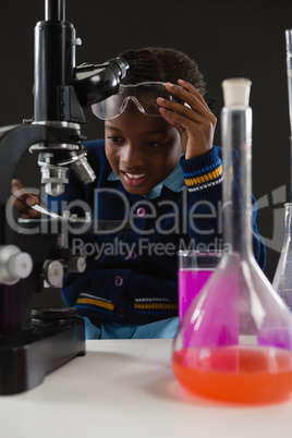 Schoolgirl using microscope against black background