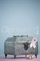 Close-up of pink Breast Cancer Awareness ribbon with chest and rings on table