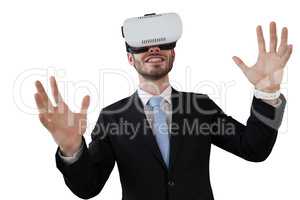 Smiling businessman with vr glasses gesturing against white background