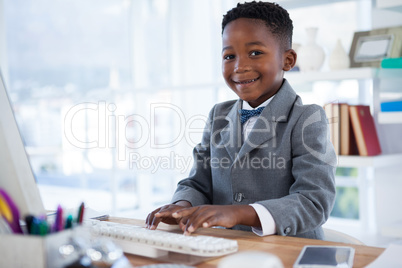 Portrait of boy imitating as businessman using computer