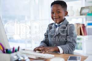 Portrait of boy imitating as businessman using computer