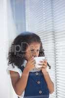 Businesswoman having coffee while standing by window