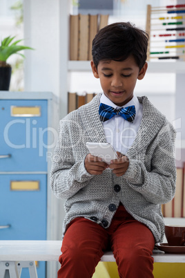 Boy pretending as businessman using mobile phone