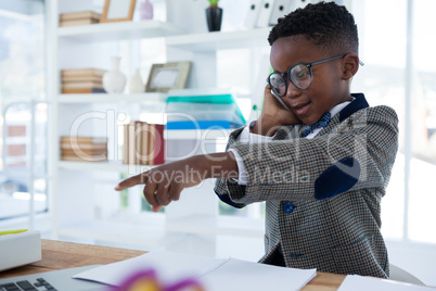 Businessman talking on phone and pointing at desk