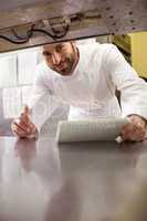 Smiling chef holding order note and digital tablet in kitchen counter