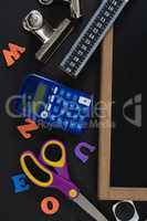 Blank slate with various school supplies on black background