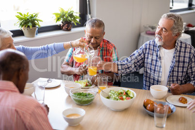 Senior woman serving drink to friends at table