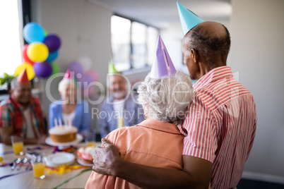 Rear view of senior couple looking at friends during party