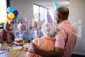 Rear view of senior couple looking at friends during party