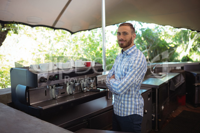 Male owner standing with arms crossed at outdoor cafÃ?Â©