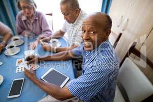 Happy senior man playing cards with friends
