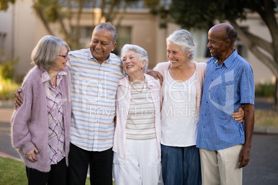 Smiling senior friends standing with arms around