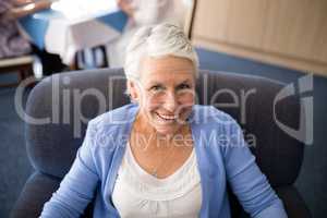 High angle view of smiling senior woman sitting on armchair