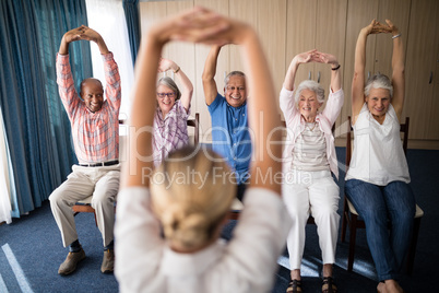 Cheerful senior men and women exercising with female doctor
