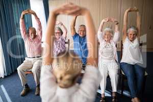 Cheerful senior men and women exercising with female doctor