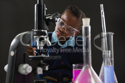 Schoolgirl using microscope against black background