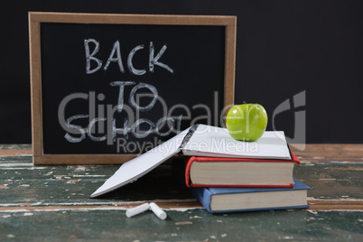 Books, apple and slate board with back to school text