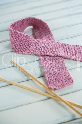 Close-up of pink woolen Breast Cancer Awareness ribbon by crochet needles