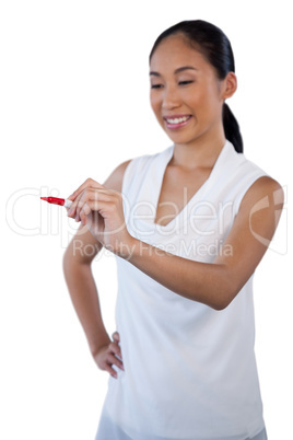 Smiling businesswoman with hand on hip writing on invisible glass