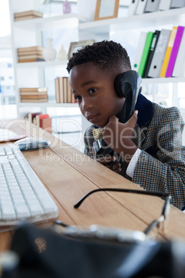 Boy imitating as businessman talking on landline phone