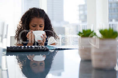 Businesswoman having coffee while sitting at desk