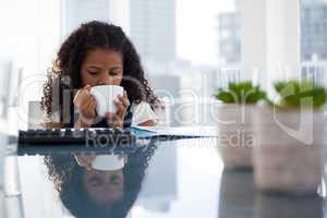 Businesswoman having coffee while sitting at desk