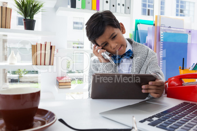 Businessman holding tablet computer while talking on smartphone