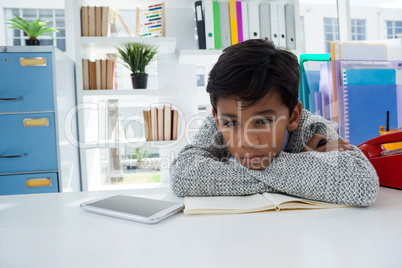 Bored businessman looking away while leaning on desk