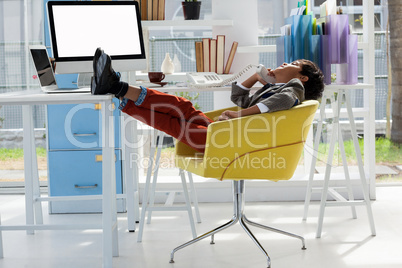 Businessman talking on landline phone while sitting on chair with feet up