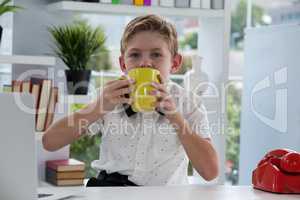 Portrait of businessman drinking coffee from yellow mug at desk