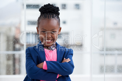 Portrait of cheerful businesswoman standing with arms crossed by window
