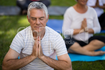 Senior man with eyes closed meditating in prayer position