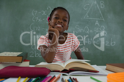 Schoolgirl reading book in classroom