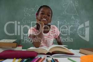Schoolgirl reading book in classroom