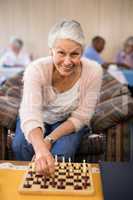 Portrait of confident senior woman playing chess at table