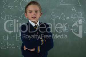 Schoolboy standing arms crossed against chalkboard
