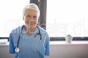 Portrait of senior doctor standing against window