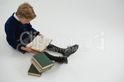 Schoolboy reading book on white background