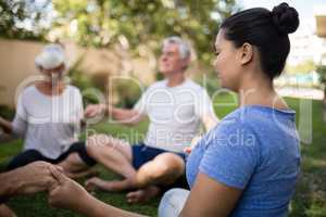 Trainer holding hands and meditating with senior people