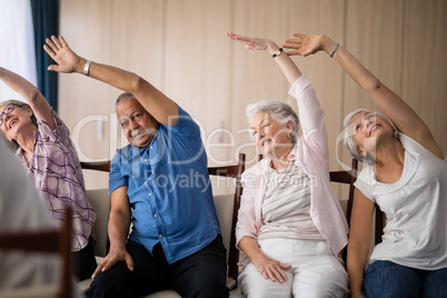 Senior people stretching while sitting on chairs