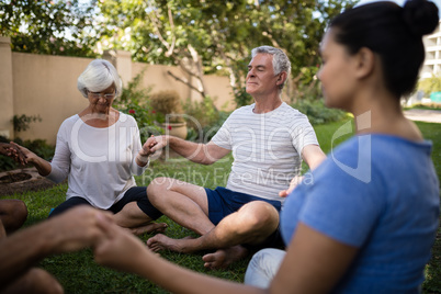 Senior people holding hands and meditating with trainer