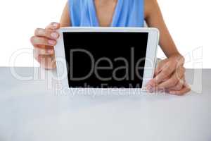 Mid section of businesswoman holding digital table at table