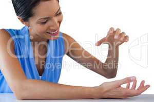 Happy businesswoman holding something while sitting at table