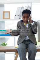 Boy imitating as businessman gesturing while talking on smartphone