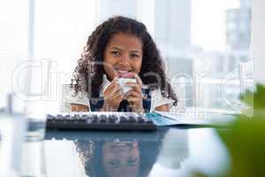 Portrait of smiling businesswoman holding coffee cup at desk