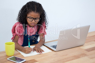 High angle view of businesswoman writing on book by laptop