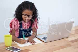 High angle view of businesswoman writing on book by laptop