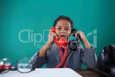 Portrait of businesswoman talking land line phones at desk