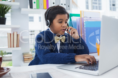 Businessman talking on microphone with head set while working on laptop