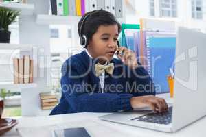 Businessman talking on microphone with head set while working on laptop